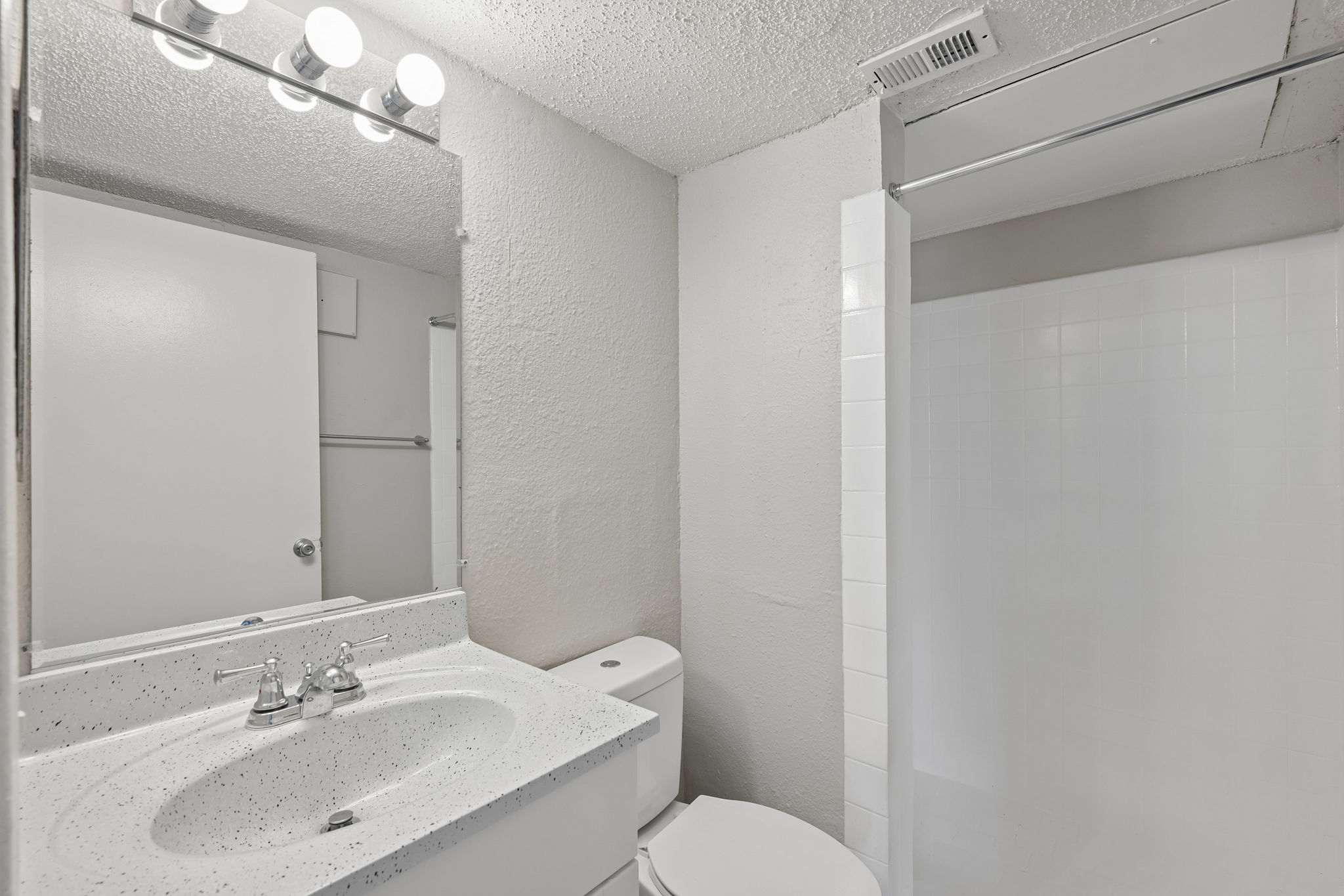 A white bathroom with a sink, toilet, and mirror.
